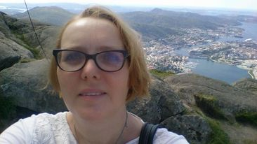 Reidun Breivik Andersen med briller og lyst h&aring;r, tar en selfie mens hun st&aring;r p&aring; en h&oslash;yde med god utsikt. 