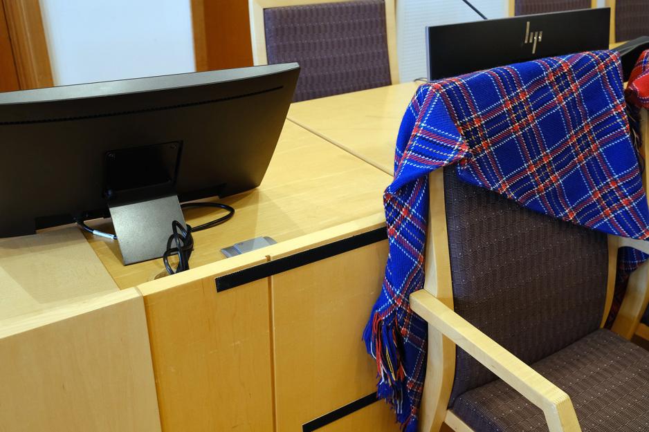 Et bl&aring;tt og r&oslash;dt plagg er over en stol i rettssalen. 