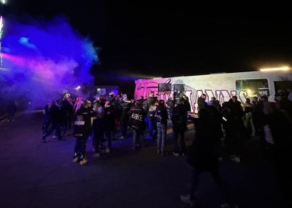 Russebusser og mange russer som st&aring;r med ryggen til og fester.