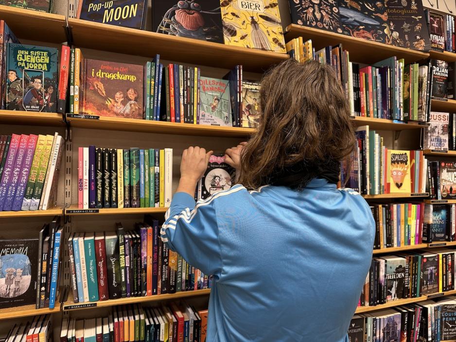 Espen trekker frem og setter b&oslash;ker p&aring; rett plass i bokhyllene