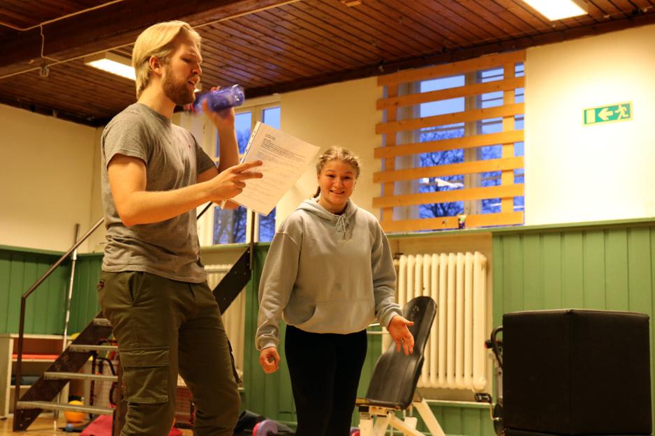 Vetle rister p&aring; en flaske og Sofie st&aring;r ved siden av og ser p&aring; han