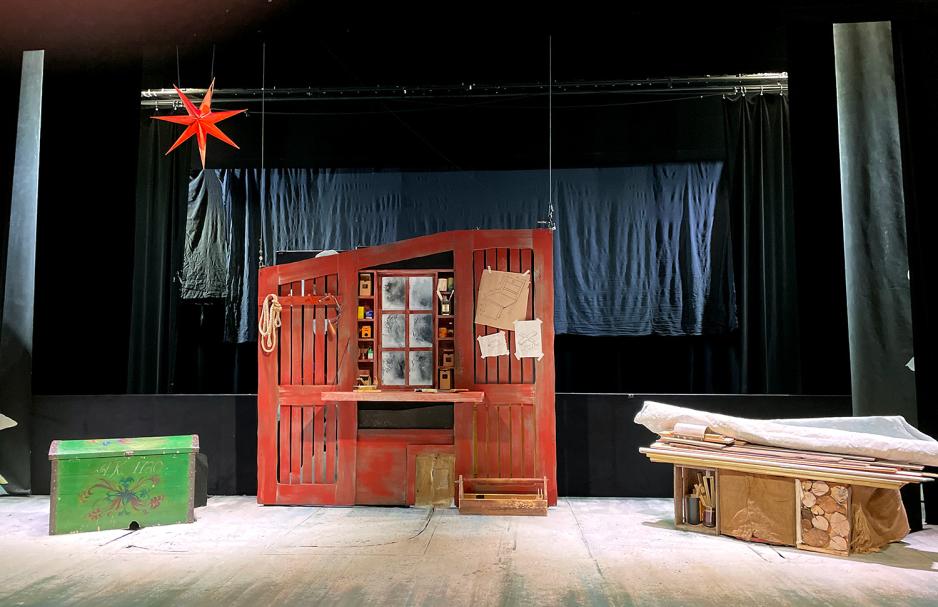 Bildet viser scenografien til forestillingen "Jul med Pr&oslash;ysen og Snekker Andersen". Et stort r&oslash;dt verksted med en gammel gr&oslash;nn kiste ved siden av. 