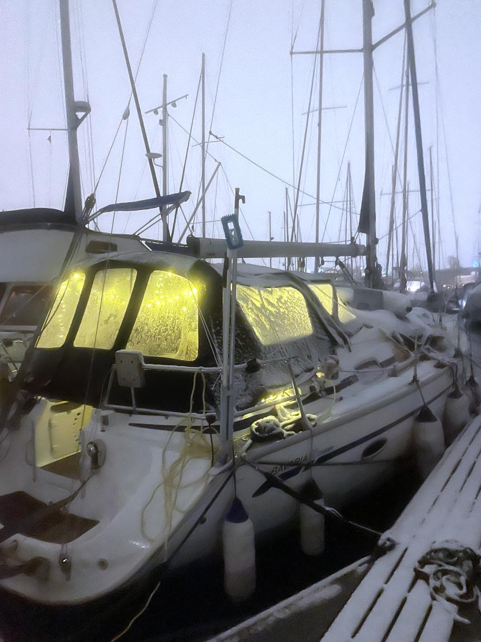 Bilde av &aring;rets f&oslash;rste sn&oslash;fall som viser den vite b&aring;ten med et dekkende lag med hvitt sn&oslash;. B&aring;ten er pyntet med julelys og v&aelig;ret er litt t&aring;kete. 