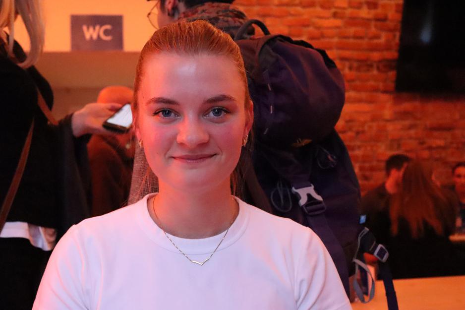 En jente med bl&aring; &oslash;yne smiler til kameraet. 