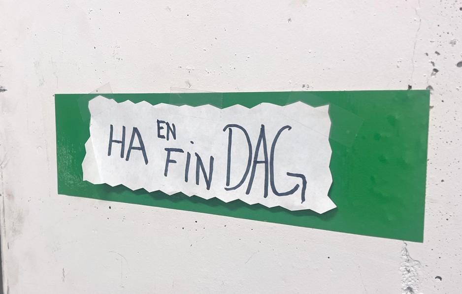 Bilde av et skilt p&aring; en vegg der det st&aring;r "Ha en fin dag". 