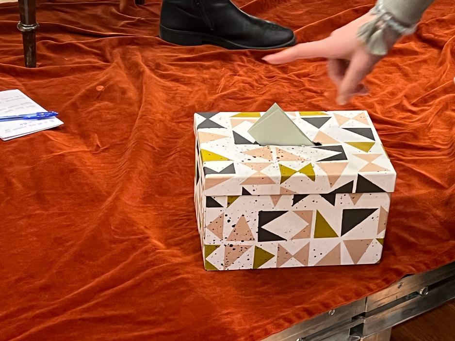 En person legger en lapp med et sp&oslash;rsm&aring;l inn i sp&oslash;rsm&aring;lsboksen. 