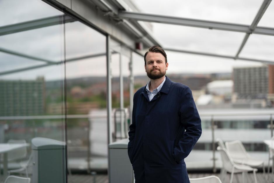 Mann med frakk som st&aring;r foran glassd&oslash;r