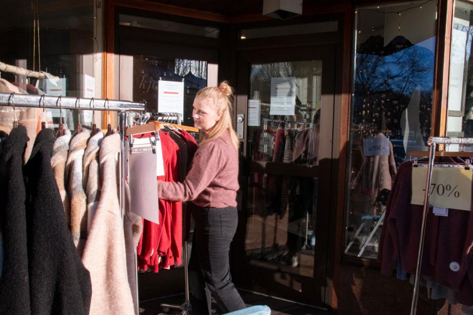 Butikkeier rydder i varene p&aring; stativer
