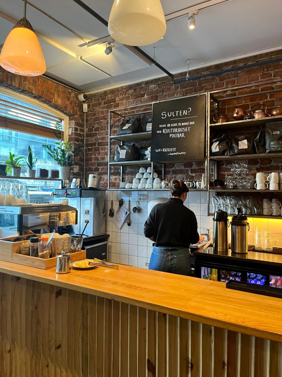 Bilde av Sunniva Sk&aring;r Styrvold som st&aring;r bak kaffebaren med ryggen til kamera og jobber med noe.