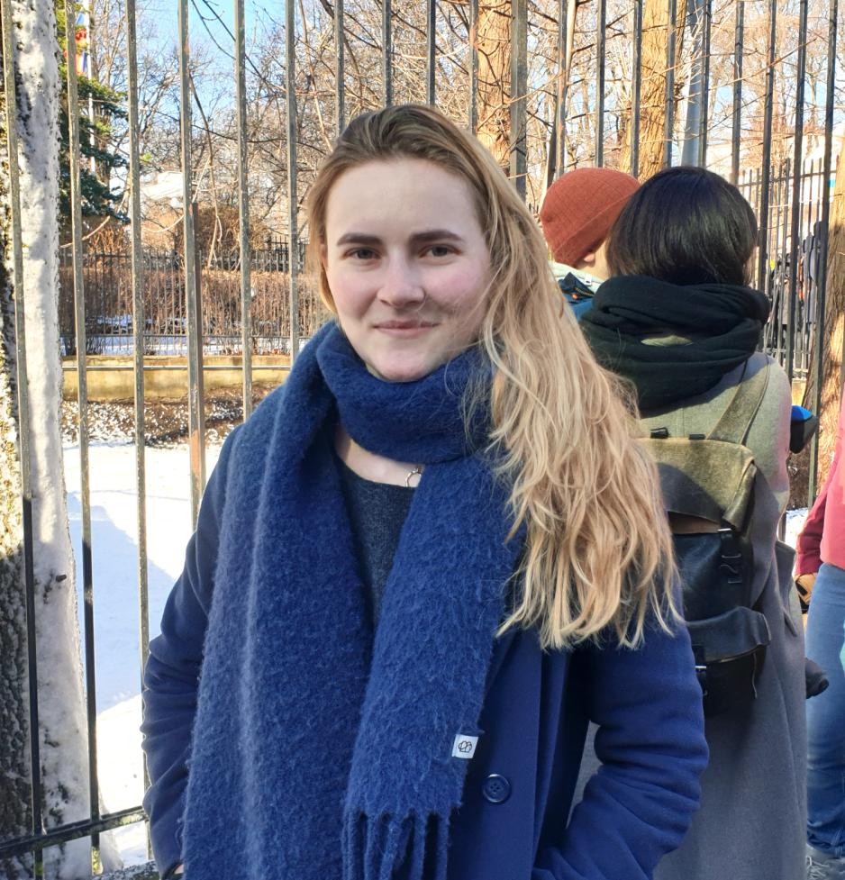 Ung, blondh&aring;ret kvinne st&aring;r i k&oslash;, kledd i bl&aring; jakke