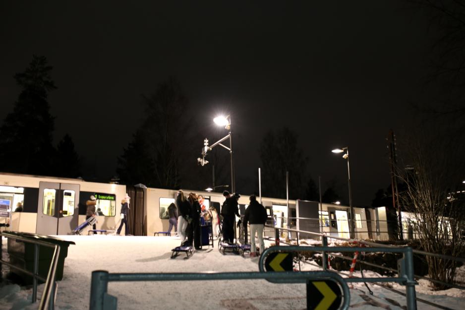 T-banen p&aring; perrongen med mennesker med kjelker i forgrunnen.