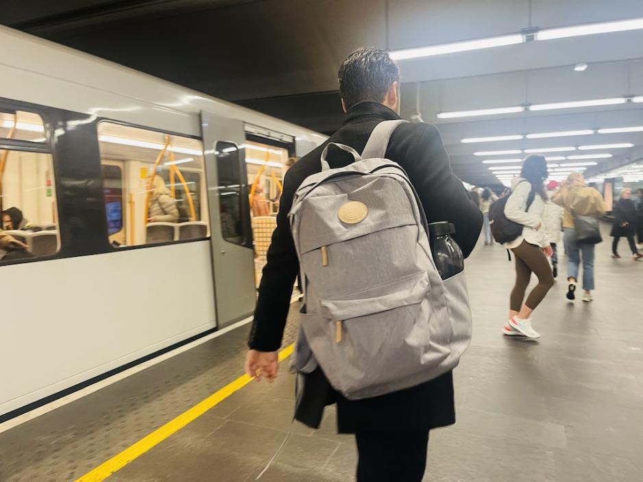 Mann med sekk g&aring;r av T-banen, sammen med mange andre ved Jernbanetorget stasjon. 