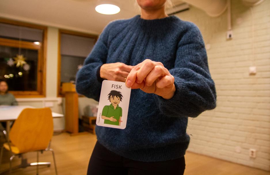 Bildet viser en h&aring;nd som holder opp et kort. P&aring; kortet er det tegnet en gutt, som holder h&aring;nden foran seg. Foran h&aring;nden er det en r&oslash;d, b&oslash;lget pil. 