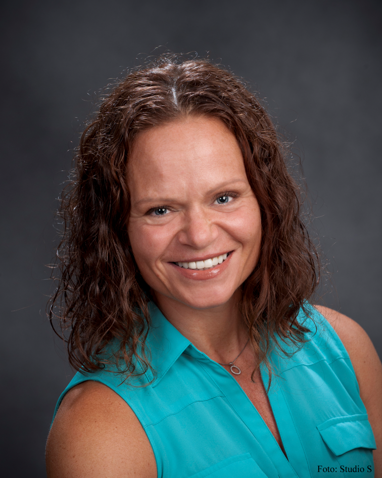 Pressebilde av Therese Fostervold Mathisen. Dame med brunt, b&oslash;lgete h&aring;r og lysebl&aring; overdel.