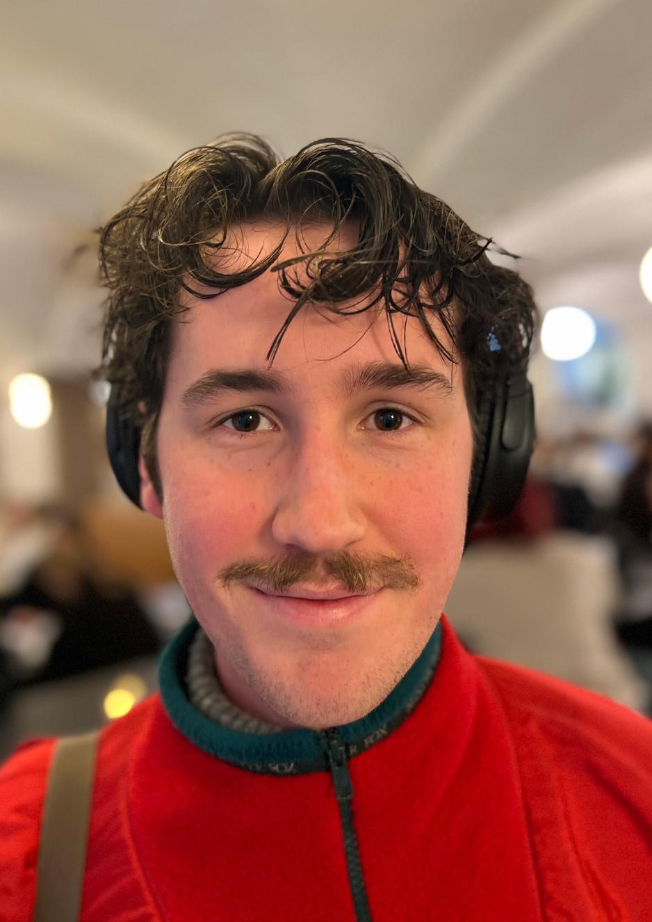 Ung mann med kr&oslash;llete brun midtskille, brun bart og ellers glattbarbert