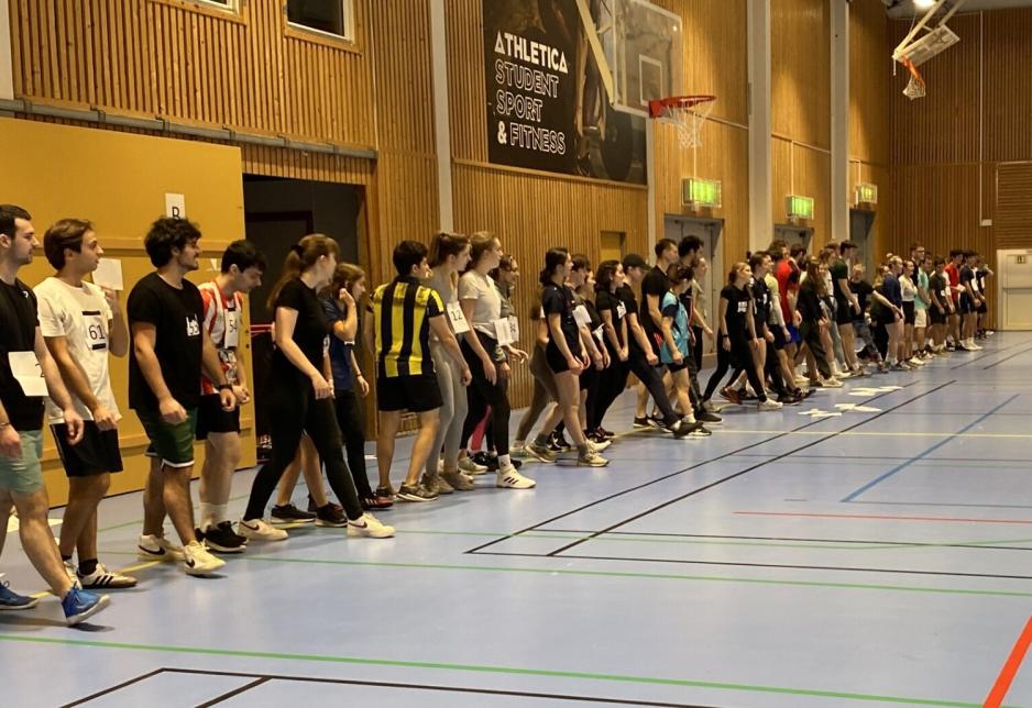 studenter p&aring; en rekke i en hall.