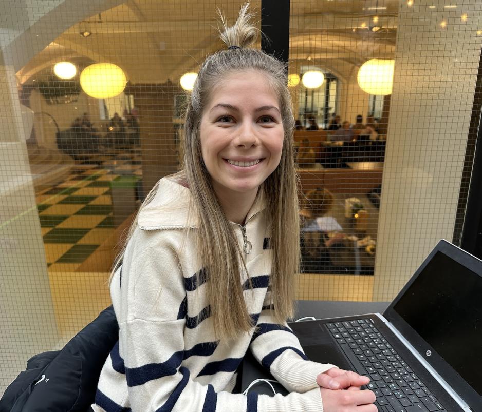 En jente med blondt h&aring;r som smiler mot kamera