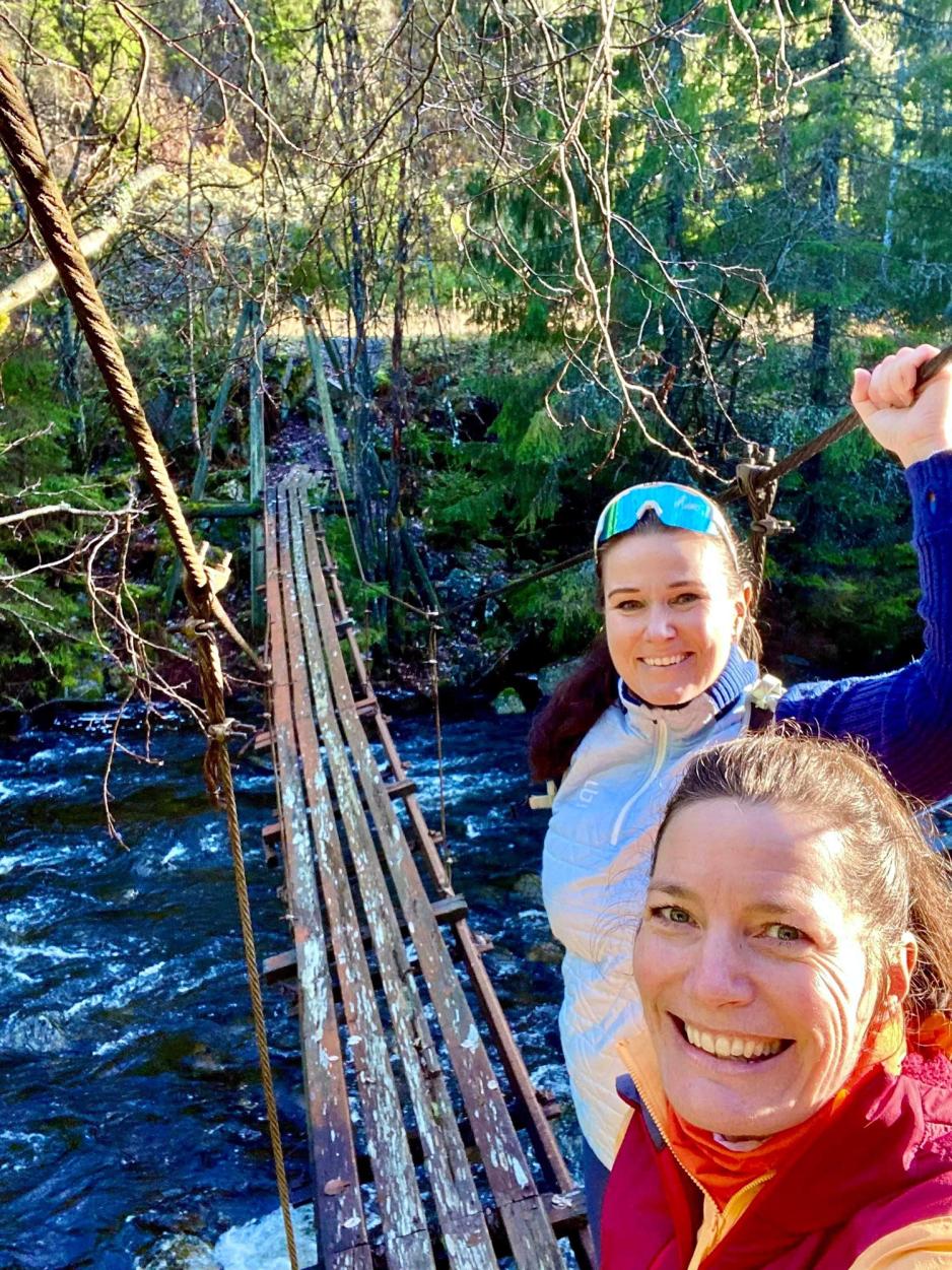 To kvinner er glade p&aring; en bru, p&aring; tur.