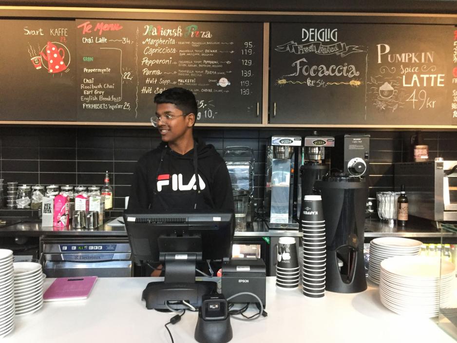 Ungdomsskoleelev demonstrerer hvordan man skal v&aelig;re vennlig overfor kunder n&aring;r man st&aring;r i kassen. 