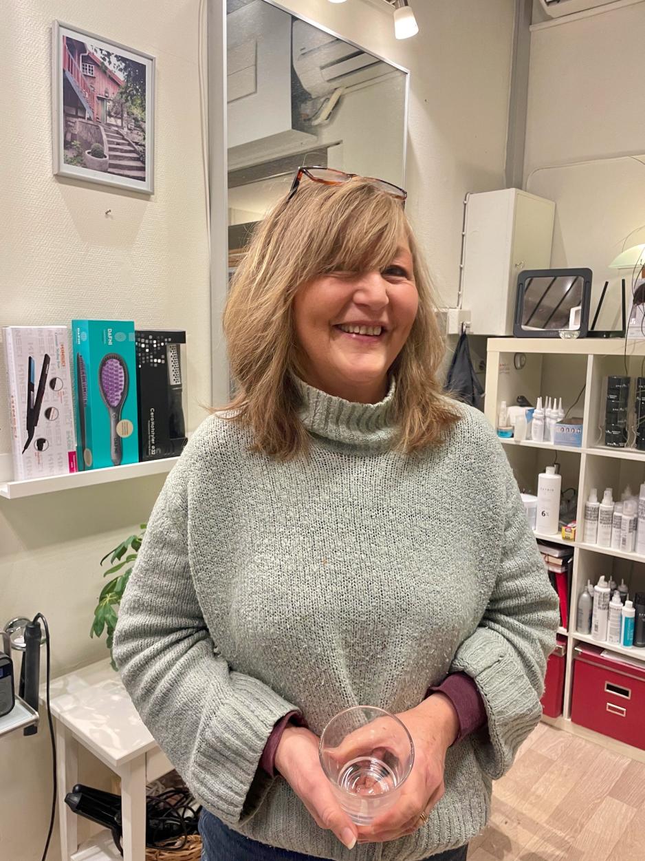 Bildet viser Senita Vesterhus som driver fris&oslash;rsalongen St. Olavs fris&oslash;r i Oslo. Hun st&aring;r avbildet i salongen sin foran et speil og hyller med sjampo og andre h&aring;rprodukter. 