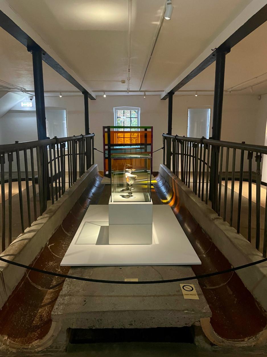 Bildet viser et gammelt trau der kuer fikk mat. Trauet har blitt bevart i galleriet p&aring; Bogstad g&aring;rd gjennom en renovering av den gamle l&aring;ven. N&aring; brukes trauet som en scene for noen av kunstverkene i utstillingen. 