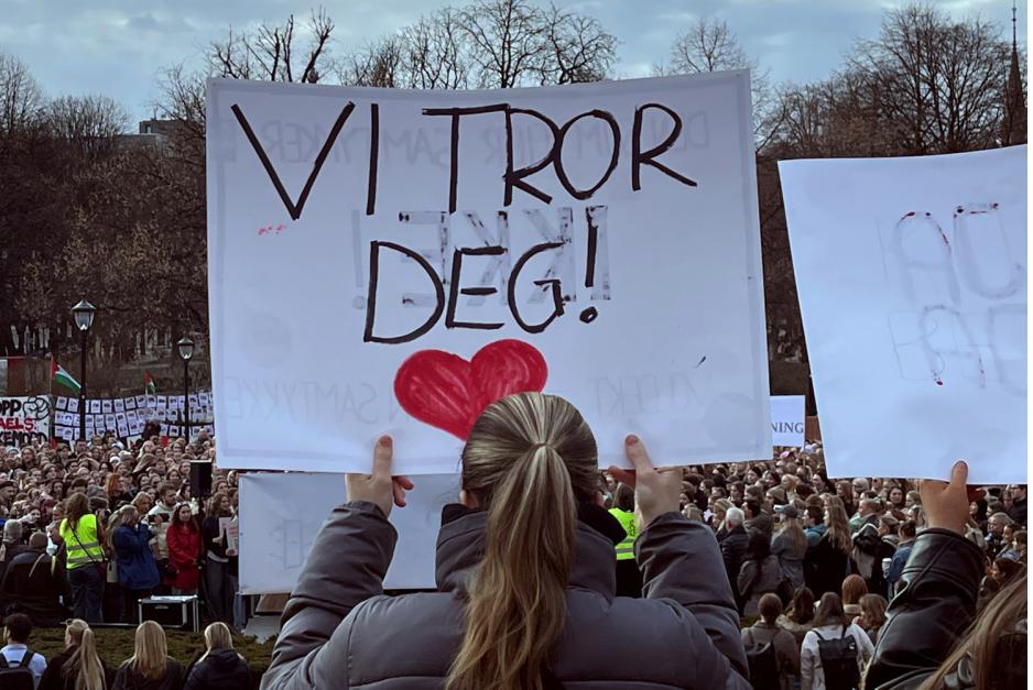 En jente holder opp et skilt der det st&aring;r "Vi tror deg"