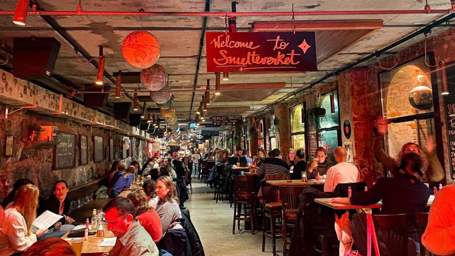 Her ser vi mange mennesker som sitter ved deres bord inne p&aring; rommet hvor musikkbingoen skal spilles. 