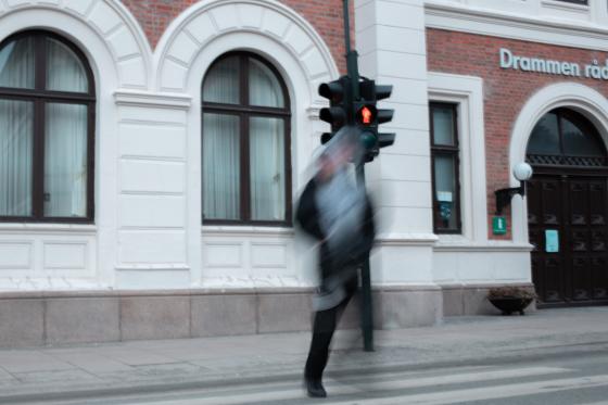 En ung gutt krysser over fotgjengerfeltet p&aring; r&oslash;dt lys. 