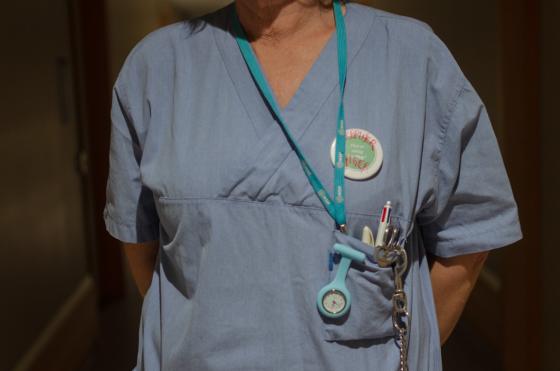 n&aelig;rbilde av sykepleieruniform, den er bl&aring; og har en klokke i lomma og en navnetag