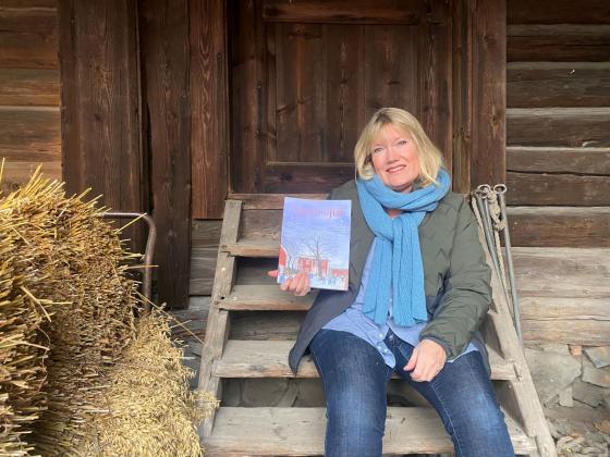Dame som sitter p&aring; en trapp, hun holder et magasin som heter Sagenejul. Bildet er tatt p&aring; V&oslash;ienvolden g&aring;rd. 