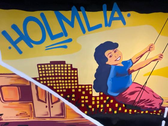 Bildet av en graffitikunst p&aring; OsloMet sine lokaler p&aring; Holmlia senter. Kunsten viser ei smilene jente p&aring; en huske og Holmlia skrevet i bl&aring; tekst over henne