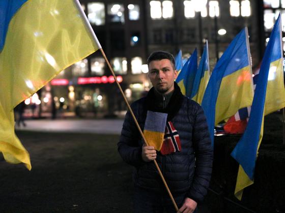 Rostyslav Yevdiukhin st&aring;r p&aring; Eidsvoll plass mens han holder en flaggstang med et Ukrainsk flagg