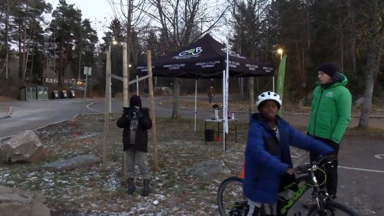 To gutter og en instrukt&oslash;r st&aring;r foran et telt. Den ene gutten drikker gl&oslash;gg, mens den andre sitter p&aring; en sykkel.