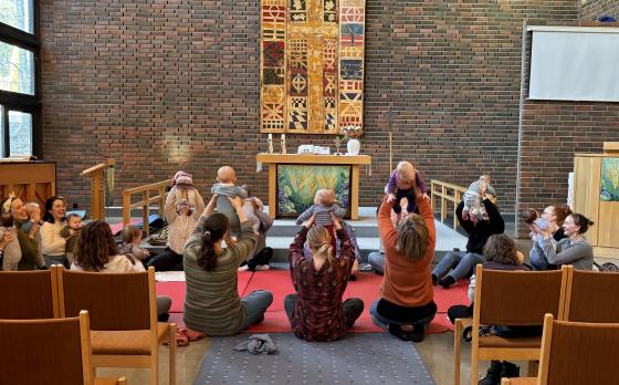 Tre m&oslash;dre holder babyene sine opp foran alteret under babysang p&aring; R&oslash;dtvedt kirke.