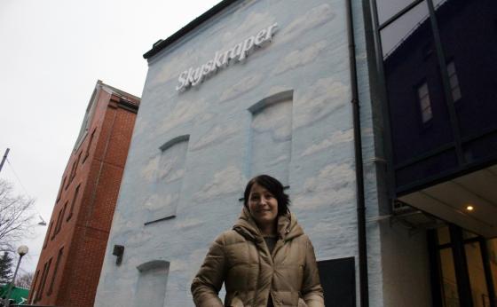 Dame foran bygning med skyer p&aring;