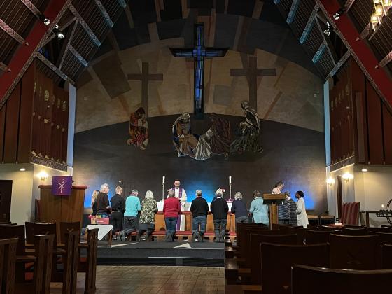 En gjeng mennesker kneler ved alteret