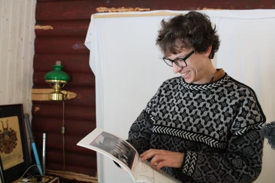 mann smiler og ser p&aring; bok