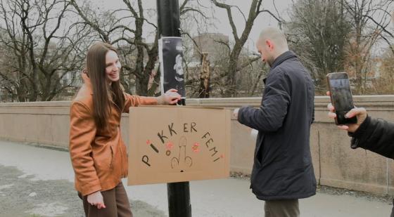 Johanna og hennes venner henger opp en plakat som sier "Pikk er femi"