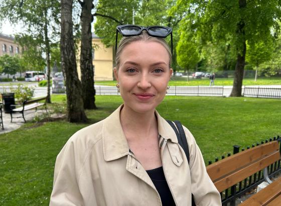 Ung dame som smiler til kamera mens hun venter p&aring; bussen.