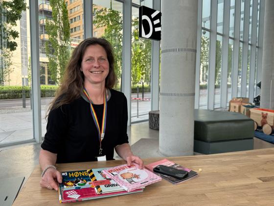 Siri Larsen smiler og viser frem noen b&oslash;ker for de minste barna