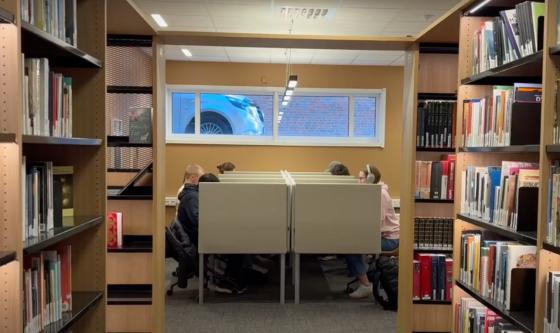 Et bibliotek med b&aring;ser og studenter som leser