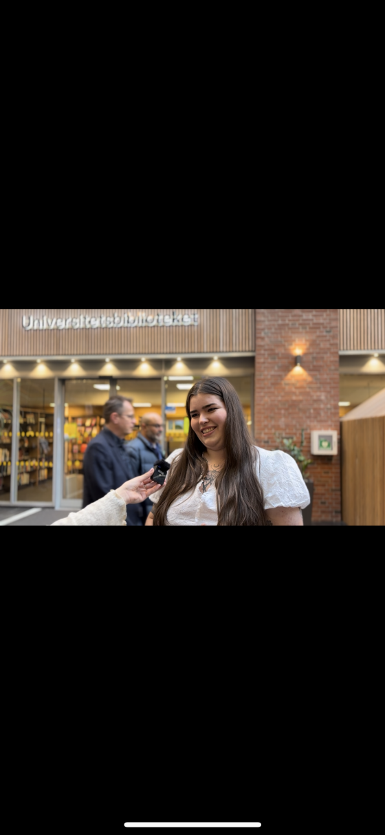 en jente som intervjues, hun smiler etter ferdig intervju utenfor studentbiblioteket