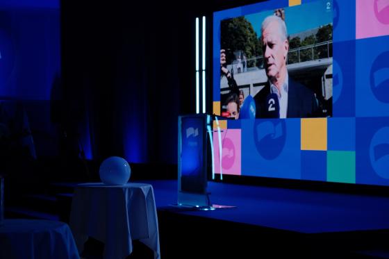 Talerstolen plassert midt p&aring; scenen, med Jonas Gahr St&oslash;re p&aring; skjermen i bakgrunnen