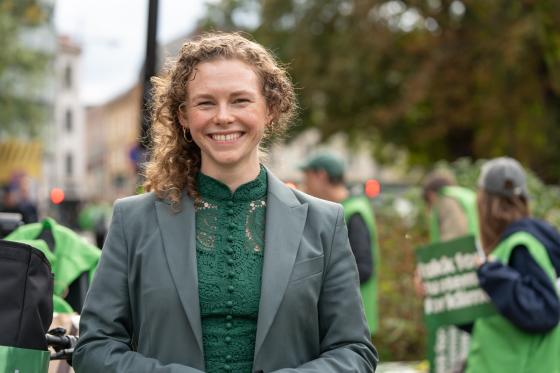 En dame, med MDG representater if&oslash;rt gr&oslash;nne vester i bakgrunnen