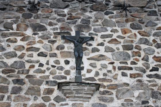 På en steinvegg, henger et kors med Jesus på