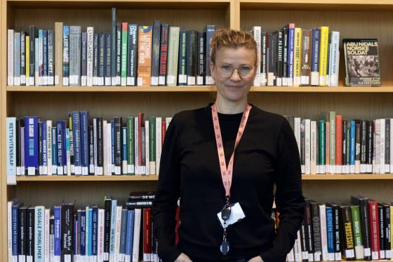 Frid Hamsun st&aring;r foran en bokhylle. Hun er seksjonsleder p&aring; Deichman Lambertseter