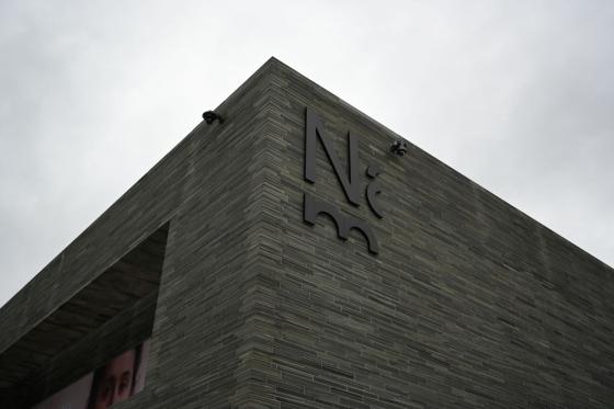 Foto av utsiden av Nasjonalmuseet foran en grå himmel