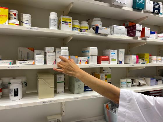 Bilde av medisiner og en h&aring;nd som strekker seg mot en eske med medisin