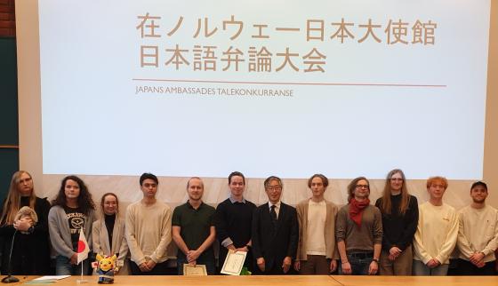 En rekke med unge mennesker st&aring;r ved et podie