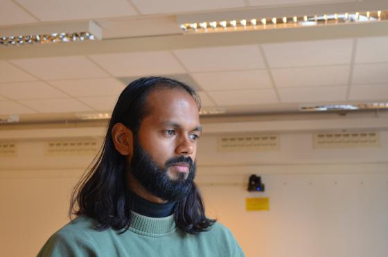 En mann i gr&oslash;nn genser st&aring;r og ser ut vinduet.